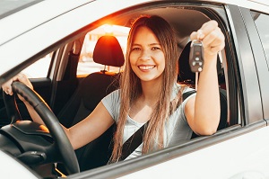 Young happy woman showing the key of new car